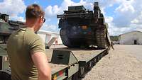 Ein Panzer fährt auf einen Sattelauflieger 