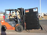 Gabelstapler unterwegs mit deutschen Hilfsgütern Ein Gabelstapler fährt eine hohe, schwarz verpackte Kiste mit Deutschland und EU-Fahne darauf über ein Rollfeld