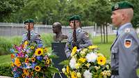 Büste eines Soldaten in Uniform, daneben stehen Soldaten des Wachbataillons