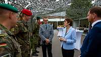 Zwei Zivilisten und drei Soldaten stehen zusammen und unterhalten sich.