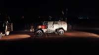 Ein militärisches Fahrzeug steht in der Dunkelheit unter einem Lichtstrahl