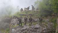 Soldaten seilen sich von einer Felswand ab. Eingesetzte Rauchgranaten erzeugen Nebel.