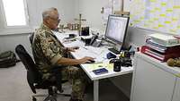 Der Militärpfarrer sitzt an seinem Computertisch und arbeitet.