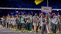 Sportlerinnen und Sportler laufen in ein Stadion ein
