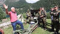Vor einem alten Geschütz stehen Soldaten und folgen den Erläuterungen eines Zivilisten in einem hellroten Poloshirt.