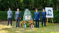 Vier Soldaten stehen um einen Gedenkstein