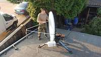 Ein Soldat steht auf einem Dach und justiert eine Satellitenschüssel