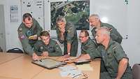 Six men wearing pilot uniforms sitting around a table during a meeting