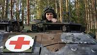 Ein Soldat mit Funkhaube schaut aus seiner Kommandantenluke in die Kamera