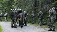 Soldaten beladen mehrere Maultiere mit Gepäck.