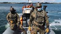 Soldaten in Flecktarnuniform stehen vorne in einem grauen Festrumpfschlauchboot.