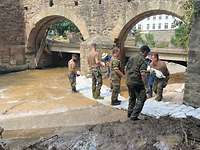 Soldaten und Angehörige des THW bauen einen Damm aus Sandsäcken.