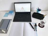 Homeschoolingprojekt CARE Gestellte Bildszene mit Laptop, Wasserglas, Notizbuch, Schreibstift und Zirkel