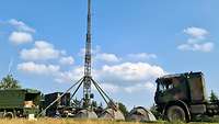 Soldaten haben ein Lager mit Zelten, Fahrzeugen und einer Antenne aufgebaut.