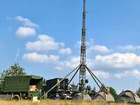 Soldaten haben ein Lager mit Zelten, Fahrzeugen und einer Antenne aufgebaut.