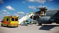 Airbus A310 auf dem Flugfeld, an der seitlichen Ladeklappe wird ein Patient ausgeladen, davor steht ein Rettungsfahrzeug