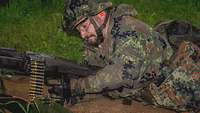 Ein Soldat liegt mit einem Maschinengewehr in Stellung und trainiert die Abläufe zum Laden der Waffe.