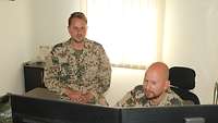 Zwei Soldaten sitzen im Büro und schauen auf die PC-Monitore