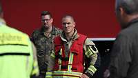 Ein Soldat in feuerfester Uniform steht auf einem Flugfeld.