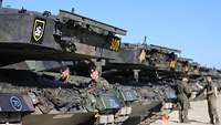Mehrere Kampfpanzer stehen aufgereiht auf einer Schotterstraße