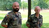 Zwei Soldaten stehen in einer Grünanlage für ein gemeinsames Portraitbild.