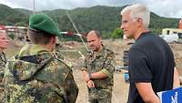 Mehrere Soldaten und ein Zivilist stehen zusammmen und reden ernst miteinander.