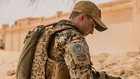 Ein Soldat mit Basecap macht im Schatten eine kurze Pause