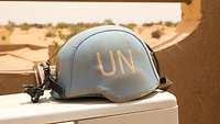 Ein Gefechtshelm der Bundeswehr mit einem blauen Helmbezug der UN