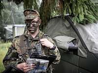 Zugführer Johannsen Soldat mit Tarnschminke im Gesicht bedient sein digitales Funkgerät.