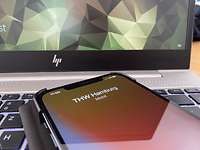 Ein Mobiltelefon liegt auf einem offenen Laptop. Darauf ist ein Anruf des THW Hamburg zu sehen