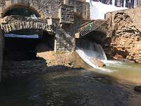 Im Bild sind zwei Torbögen. Durch den einen fließt Wasser. Der zweite Bogen ist von einem Sandsackwall geschützt 