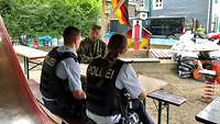 Ein Soldat und zwei Mitarbeitenden der Polizei sitzen an einem Tisch und reden