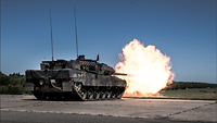 Ein Kampfpanzer Leopard bei der Schussabgabe. Aus dem Rohr sticht eine große Feuerfontäne 