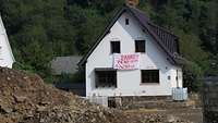 An einem zerstörten Haus hängt ein Plakat mit der Aufschrift „Danke allen Helfern“.