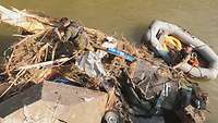 Ein Soldat befestigt ein Seil am Treibholz in einem Fluss, ein anderer Soldat im Schlauchboot daneben