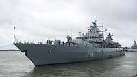 Ein grauses Schiff legt von der Pier ab.