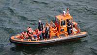 Ein orange farbenes Boot der Bundespolizei mit Zivilisten in Schwimmwesten an Bord.