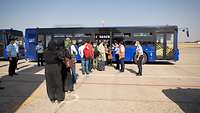 Menschen steigen in einen Shuttlebus am Flughafen in Taschkent