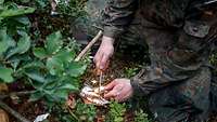 Mit einem Magnesiumstab und einem Taschenmesser macht ein Soldat Feuer.