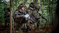 Im Wald knien drei Soldaten und beobachten ihre Umgebung.