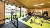 Innenansicht von einem Fitnessraum in einer Halle aus Holz. 