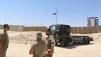 Zwei US-Soldaten und ein deutscher Soldat stehen vor einem Lkw und dahinter befindet sich das Radargerät