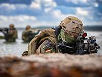 Soldiers in camouflage on position on a beach.