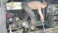 Ein Soldat arbeitet auf der Ladefläche eines LKWs an Pumpen.