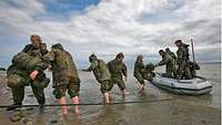 Soldiers disembark from an inflatable boat.
