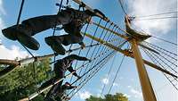 Several soldiers climb up a training mast.