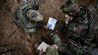 Soldat erklärt anderen Soldaten etwas auf einer Karte.