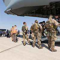 Personen verlassen im Beisein von Soldaten einen A400M über die Laderampe und laufen zu einem Shuttlebus am Flughafen Taschkent