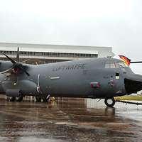 Ein graues Flugzeug mit steht auf einer verregneten Rollbahn.