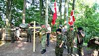 Soldaten mit zwei Schweizer Fahnen und einem Kreuz bei einer Rast